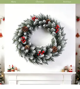 Snowy Christmas wreath with pine cones and red berries on a white wall