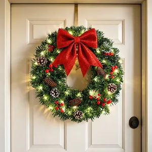 Couronne de Noël lumineuse avec nœud rouge, pommes de pin et baies pour porte