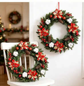 Weihnachtskränze mit roten Poinsettien, Zapfen und Baumwolle auf weißem Stuhl