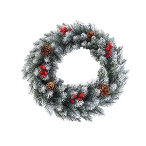 Snow-flocked Christmas wreath decorated with natural pinecones and vibrant red berries