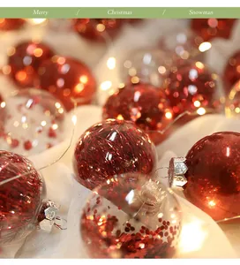 Vista dettagliata di palline di Natale rosse glitterate con luci calde su tessuto