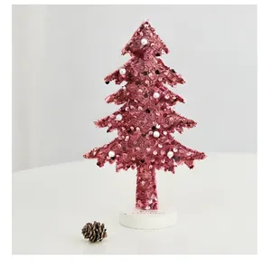 Vue détaillée d'un sapin de Noël à paillettes roses avec perles sur socle blanc
