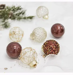 Detailopname van elegante gouden gaas en bordeauxrode glitter kerstballen op witte stof.