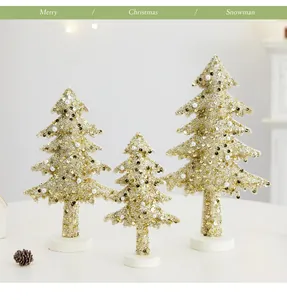 Détail de trois sapins de Noël à paillettes dorées pour une décoration de table festive.