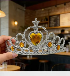 Detailed close-up of a silver princess tiara featuring a large yellow heart rhinestone