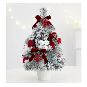 Snow-flocked mini Christmas tree with red velvet bows and berries in a white pot