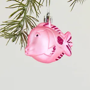 Pink fish Christmas tree ornament with glitter details on a pine branch