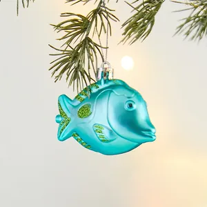 Glossy turquoise fish Christmas ornament with green glitter on a pine tree branch