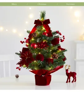 Detailed view of festive tabletop Christmas tree with red ornaments and warm LED lighting