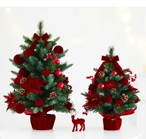 Pair of desktop Christmas trees decorated with velvet red bows, berries and festive ornaments
