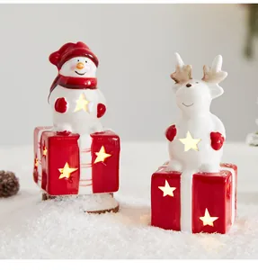 Detailansicht von leuchtenden Keramik-Schneemännern und Rentieren auf Geschenkboxen