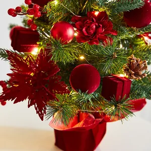 Mini pre-lit Christmas tree with red ornaments, berries, and velvet base for festive decor