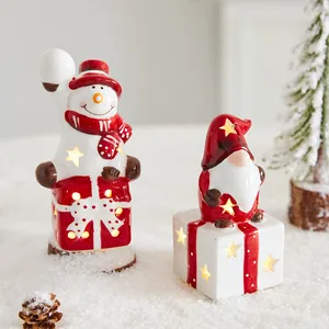 Festliche leuchtende Keramik-Weihnachtsfiguren mit Schneemann und Gnom auf Geschenkboxen