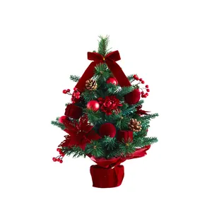 Tabletop mini Christmas tree with red velvet bows and ornaments for holiday decor.