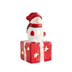 Festliche Weihnachtsfigur aus Keramik Schneemann auf leuchtender Geschenkbox mit LED-Sternen