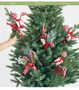 Detail of hand inserting festive red berry and candy cane branch into a green Christmas tree