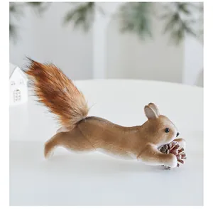 Realistic simulation squirrel Christmas ornament holding a natural pine cone on a white table