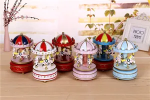 Detailed view of six colorful wind-up carousel music boxes arranged on a wooden table