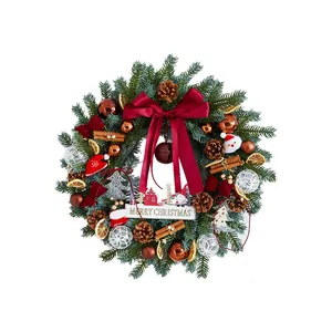 Couronne de Noël luxuriante avec nœud rouge vin, pommes de pin et décorations.