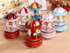Detailed view of colorful wind-up carousel music boxes on a wooden table