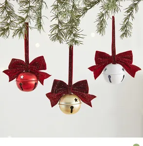 Gedetailleerde weergave van rode, gouden en witte kerstklokken met fluwelen strikken aan de boom