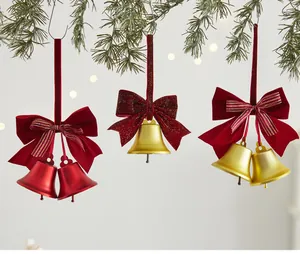 Detailed view of red and gold Christmas bell ornaments with velvet bows on pine branches