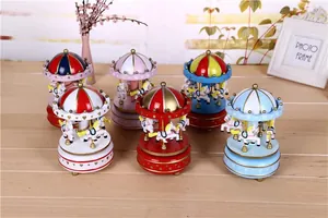 A collection of various colorful wind-up carousel music boxes on a wooden table