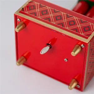 Detailed view of the winding key and mechanism on a red wooden nutcracker music box base
