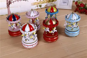 Vintage wind-up carousel music boxes in various colorful designs on a wooden table