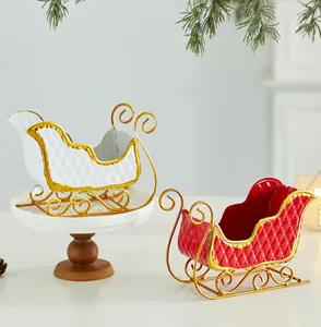 Close-up of white and red Christmas metal sleigh table decorations with gold trim.
