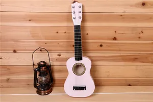Guitare pour enfant de 21 pouces en bois rose contre un mur avec lanterne vintage
