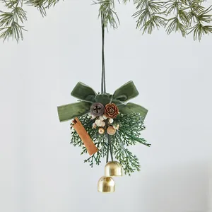 Elegante adorno navideño con lazo de terciopelo verde, piñas y cascabeles dorados.