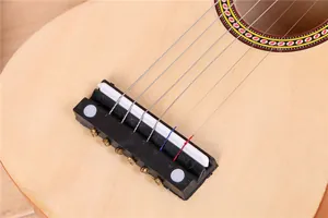 Détail du chevalet et des cordes métalliques sur une guitare acoustique en bois de 21 pouces