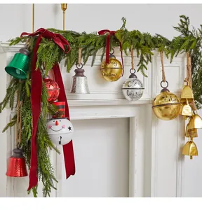Festive Christmas iron bells with Merry Christmas text hanging on a pine garland