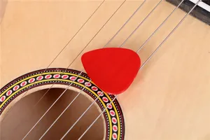 Gros plan d'un médiator rouge sur une guitare en bois de 21 pouces pour enfants