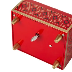 Mechanical wind-up mechanism on the bottom of a red Nutcracker music box with gold patterns