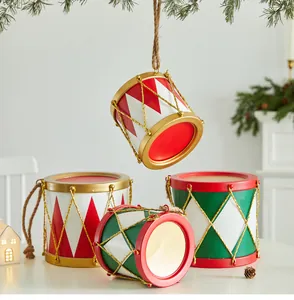 Gros plan d'ornements festifs en forme de tambour en métal rouge et vert pour Noël.