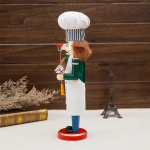 Vue latérale d'un chef casse-noisette en bois de 38 cm tenant un cupcake et fouet.