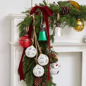 Festive Christmas iron bell ornaments with hemp rope hanging from a green garland