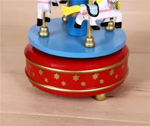 Close-up detail of a vintage wooden wind-up carousel music box with golden stars