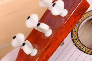 Détail des chevilles blanches et de la tête d'une guitare en bois de 21 pouces pour enfant