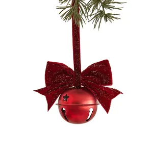Feestelijke rode kerstbel met een fluwelen strik hangend aan een groene dennentak