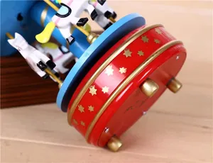 Close-up macro detail of red carousel music box base with gold stars and wind-up key mechanism