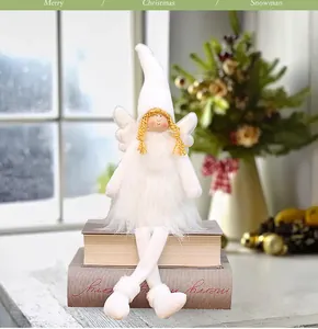 Close-up of a plush white Christmas angel doll sitting on books in a festive setting