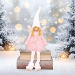 Pink plush Christmas angel doll with white wings sitting on books in winter scene