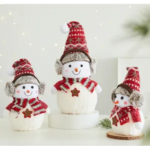 Statuette di pupazzi di neve natalizi in peluche con cappelli di maglia e paraorecchie.