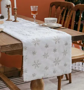 Witte pluche tafelloper met zilveren lovertjes sneeuwvlokken in een kersttafel decoratie