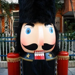 Close-up detail of a 1.8m large outdoor wooden Nutcracker soldier with black fur hat