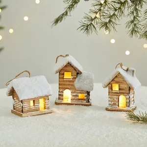 Glowing wooden miniature Christmas cabins with snow-covered roofs and warm LED lights