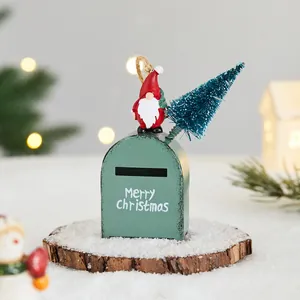 Festive green metal mailbox ornament with Santa and tree on snow-covered wood